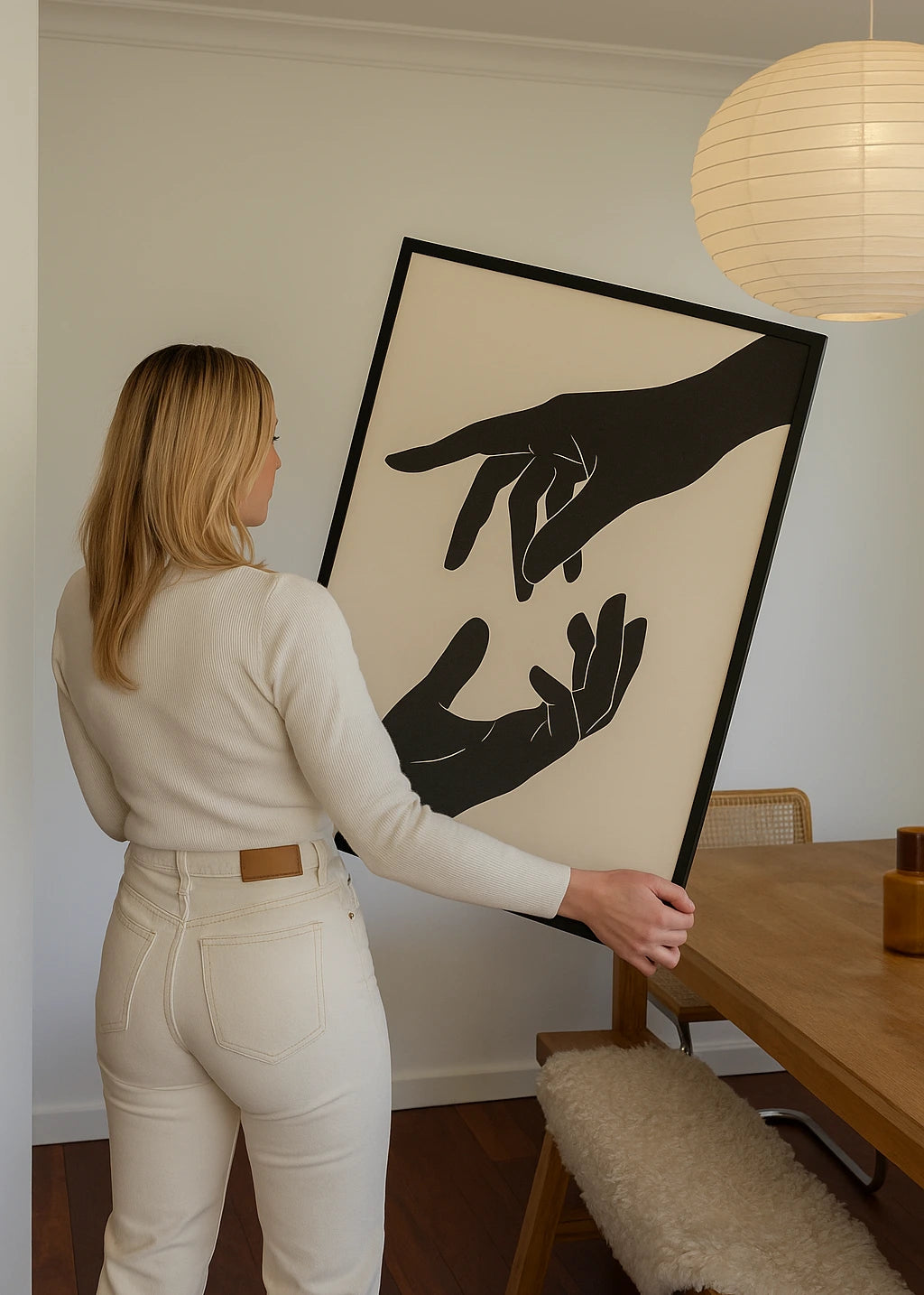 modern wooden framed artwork showing minimalist black hand illustration held by a woman in a neutral living space